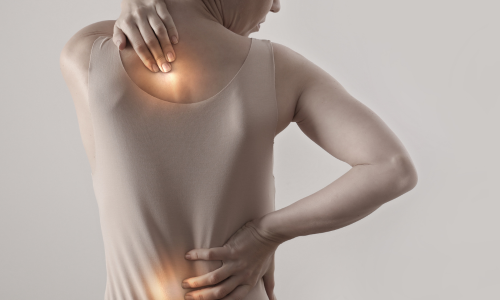 Image is of a woman holding her back that is in pain, concept of back pain treatment in Chicago