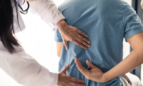 Image is of a doctor examining a patient's back, concept of back pain treatment in Chicago