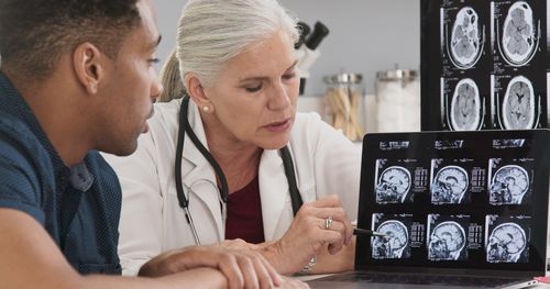 Image is of a doctor showing patient MRI images of brain, concept of concussion care