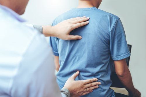 Image is of a chiropractor examining a patient's back pain.