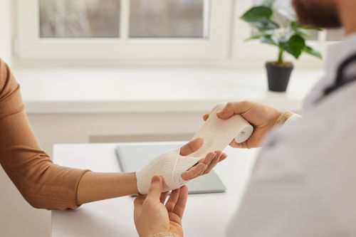 Image is of a doctor bandaging a hand injury concept of hand and wrist pain treatment in Chicago