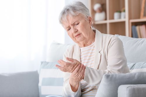 Image is of an elderly woman holding her wrist in pain concept of hand and wrist pain treatment in Chicago