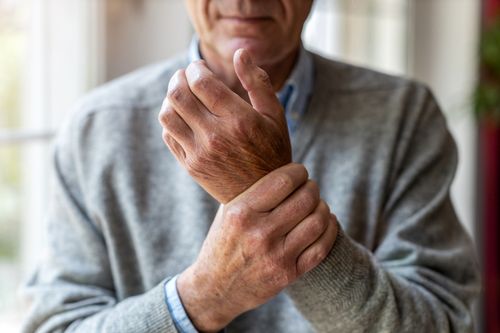 Image is of an elderly man with arthritis holding his hand that is in pain, concept of joint pain treatment in Chicago