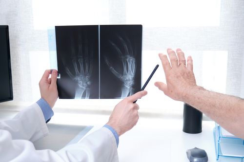 Image is of a doctor showing his elderly patient an xray of his arthritic hand concept of joint pain treatment in Chicago
