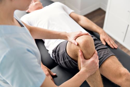 Image is of a man being treated by a physical therapist concept of knee pain treatment in Chicago