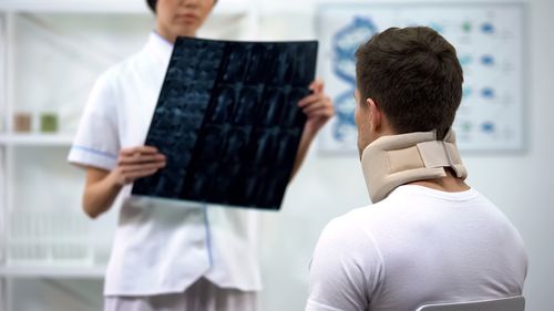 Image is of a motorcycle accident victim in a neck brace being shown mri images by a doctor concept of motorcycle accident injury treatment in Chicago