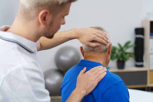 Image is of an elderly man having his neck looked at by a young doctor concept of neck pain treatment in Chicago