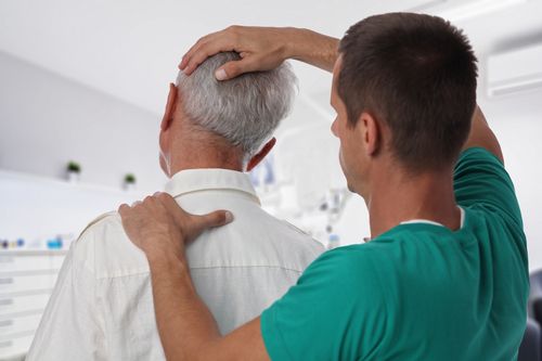 Image is a male physician helping patient with neck pain concept of whiplash treatment in Chicago 