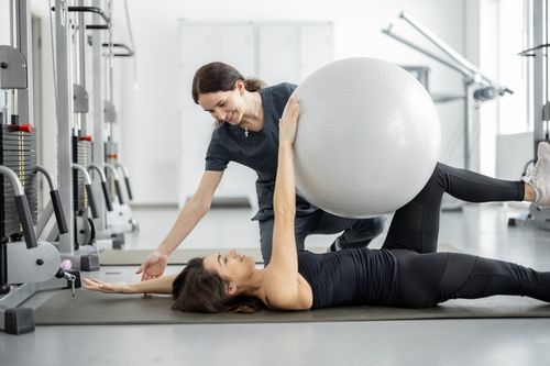 Image is of a woman helping a pain patient do physical therapy exercises, concept of pain management in Chicago
