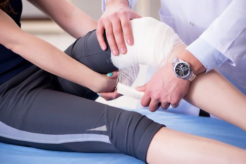 Image is of a physician wrapping the knee of a patient concept of Hazel Crest injury treatment center