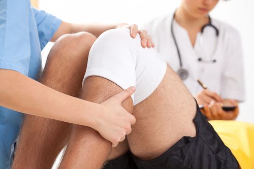 Image is of a physician examining a patient's injured knee, concept of surgical treatments for injuries in Chicago