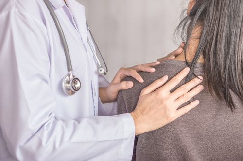 Image is of a female physician examining a female patient's neck pain concept of Woodridge injury treatment center