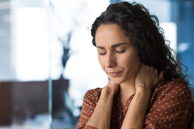 Image is of a woman in pain and holding the back of her neck, concept of things to know about pain management