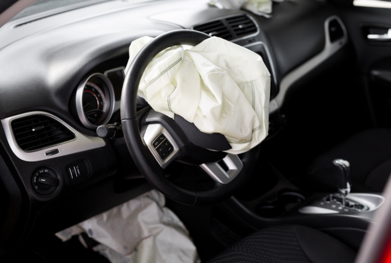 Image is of a car with a deployed airbag concept of common airbag injuries