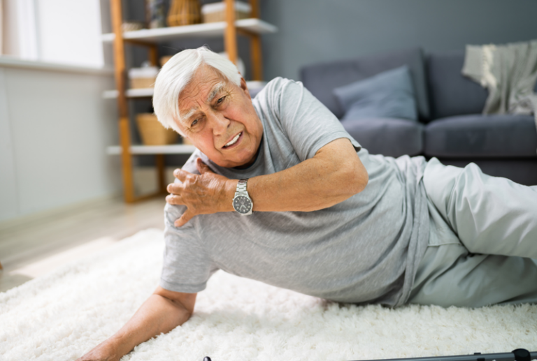 Image is of n elderly man who has fallen and is holding his shoulder in pain, concept of common slip and fall injuries