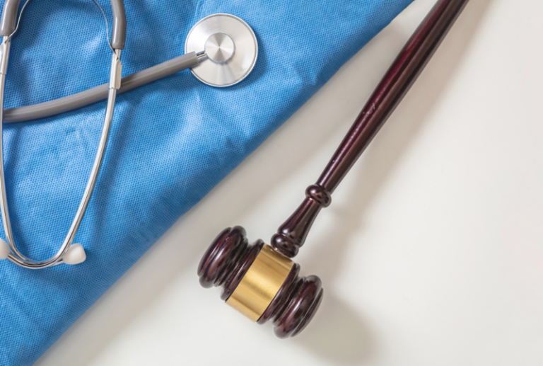 Image is of a stethoscope next to a judges gavel, concept of surgery and personal injury settlements