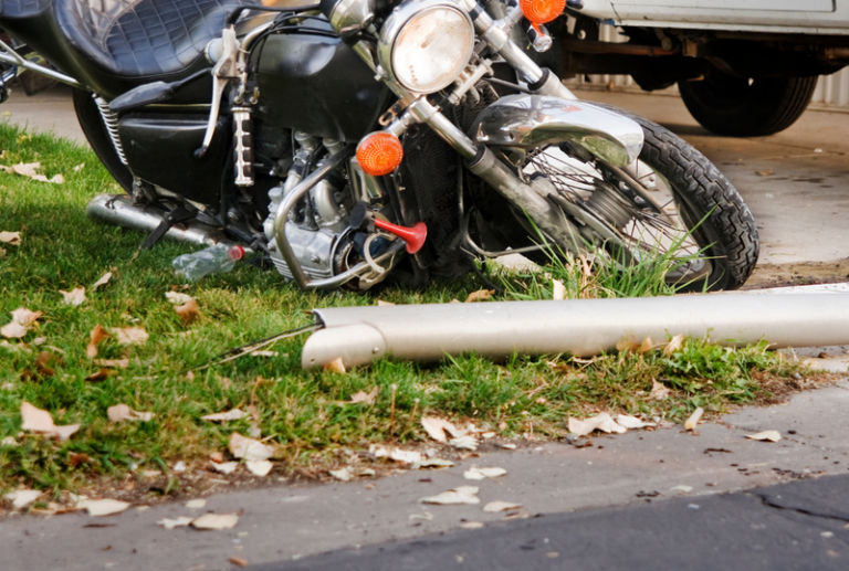 Image is of a motorcycle that crashed into a pole due to being hit by a car, concept of motorcycle accident pain treatment