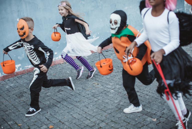 Image is of a group of young kids in Halloween costumes going trick-or-treating, concept of prevent injuries on Halloween