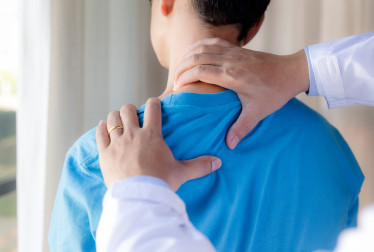 Image is of a male patient having his shoulder manipulated by a chiropractor, concept of chiropractic care after an injury